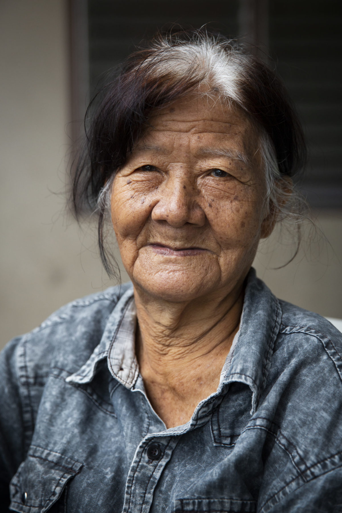 A person with graying hair wearing denim smiles. 
