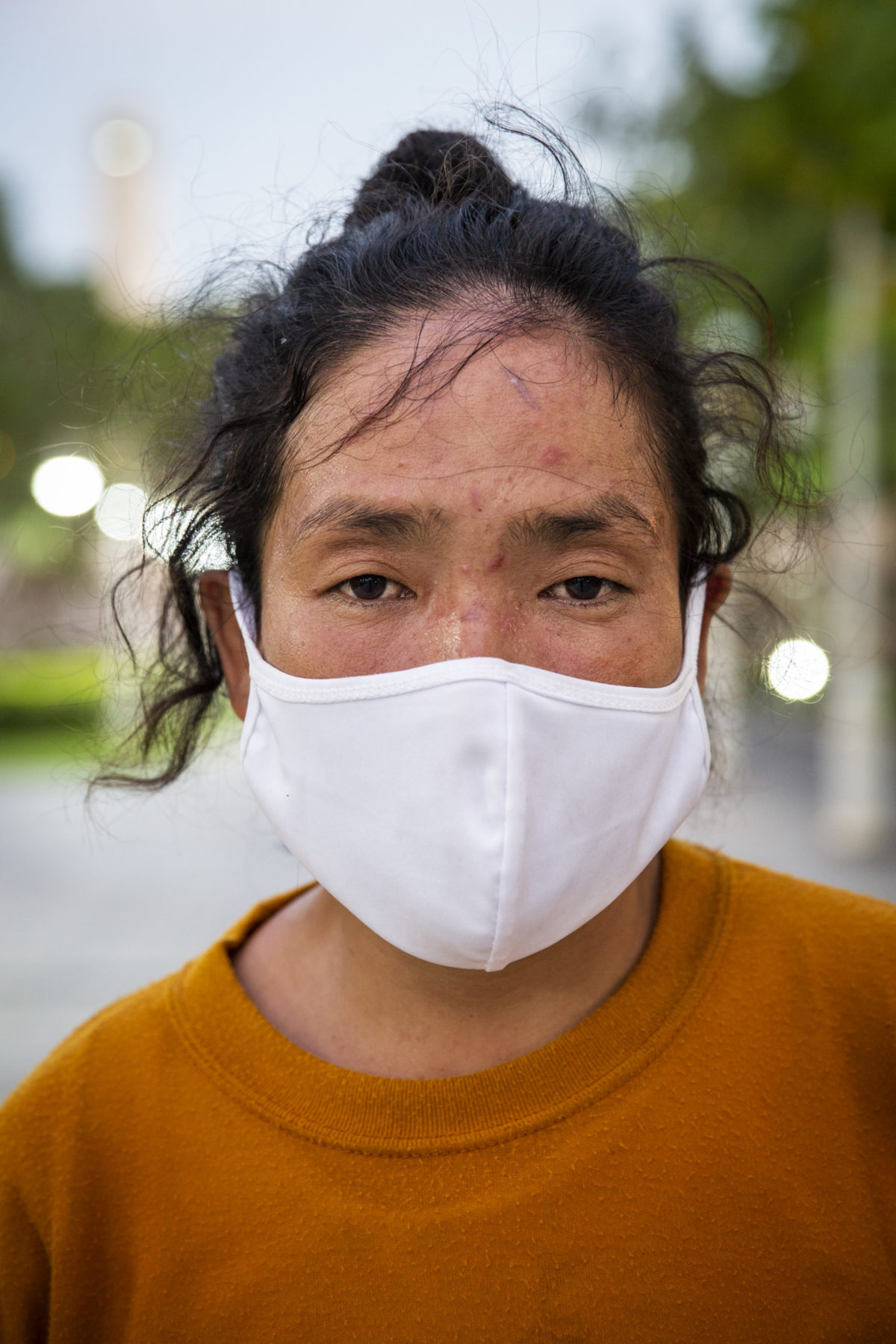A young person wearing orange and a white mask. 