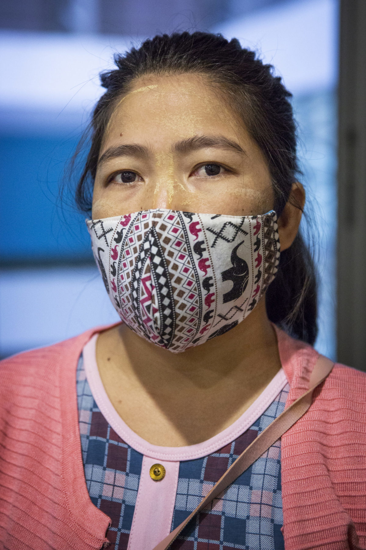 A young person wearing a mask looks forward. 
