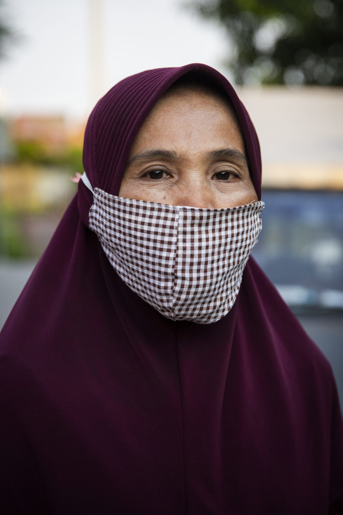 A person wearing a mask over their head covering. 