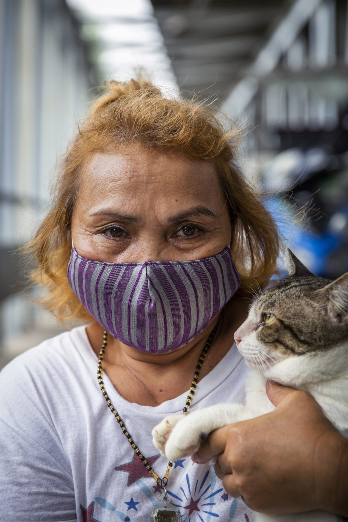 A person in a mask holds their cat in one arm. 