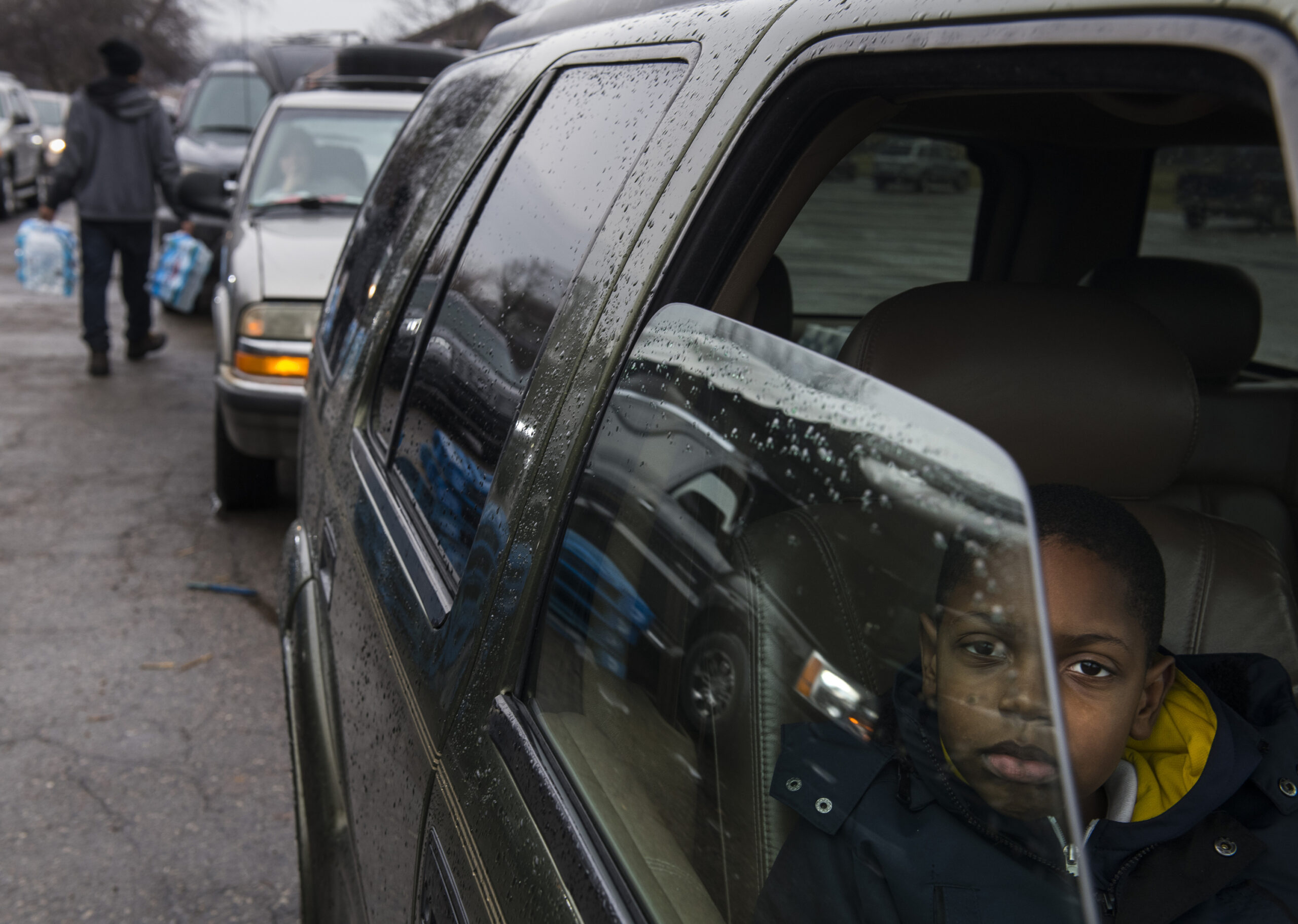 Side view of a car looking into the front passenger seat where a child in a blue coat is looking at the camera.