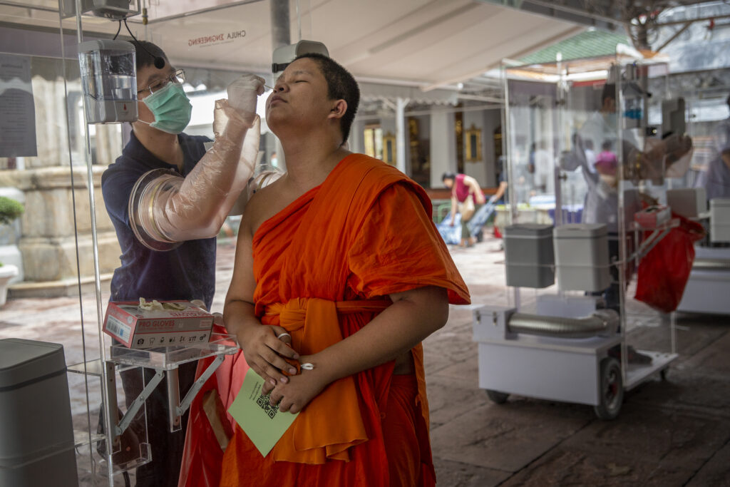 A Buddhist monk receives a medical test from a volunteer at a mobile testing site.
