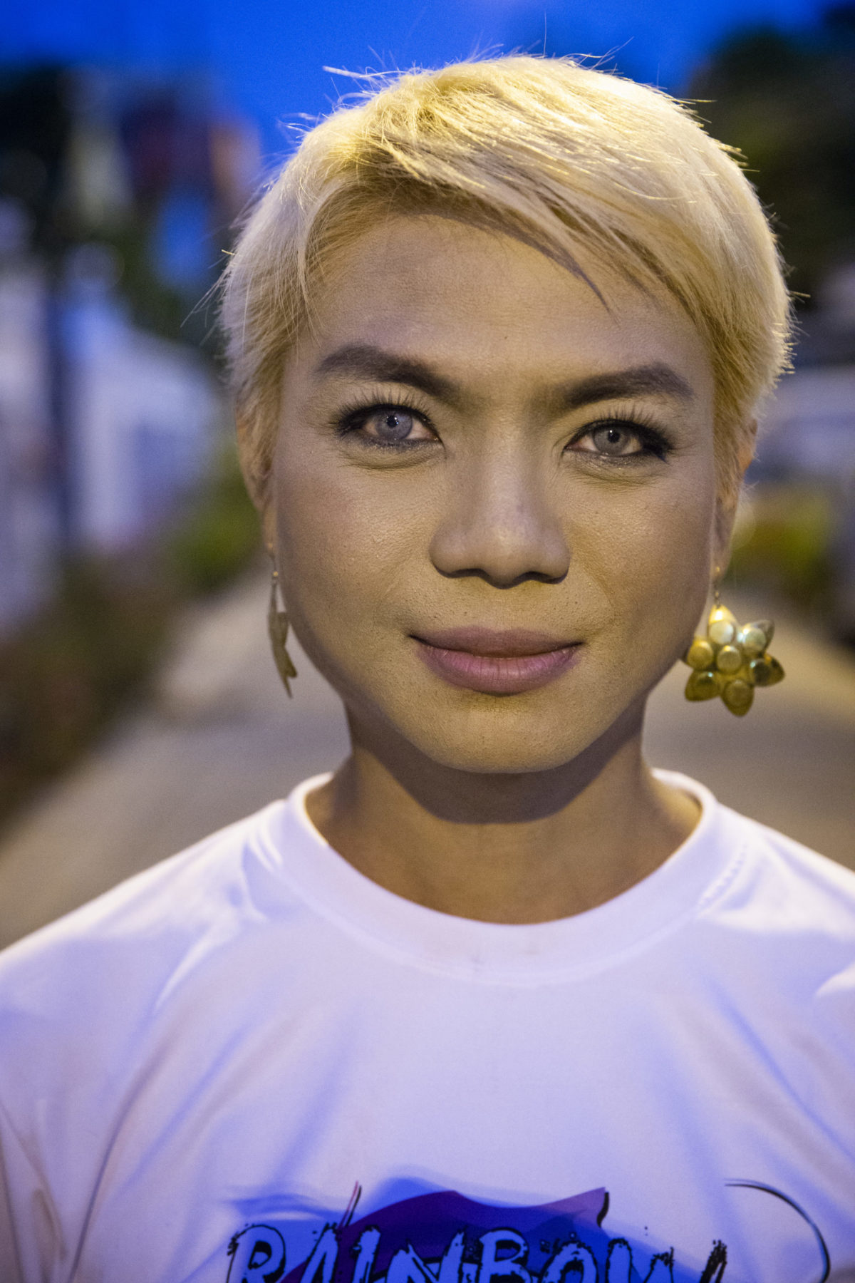 A person wearing a white tee smiles for a photo.