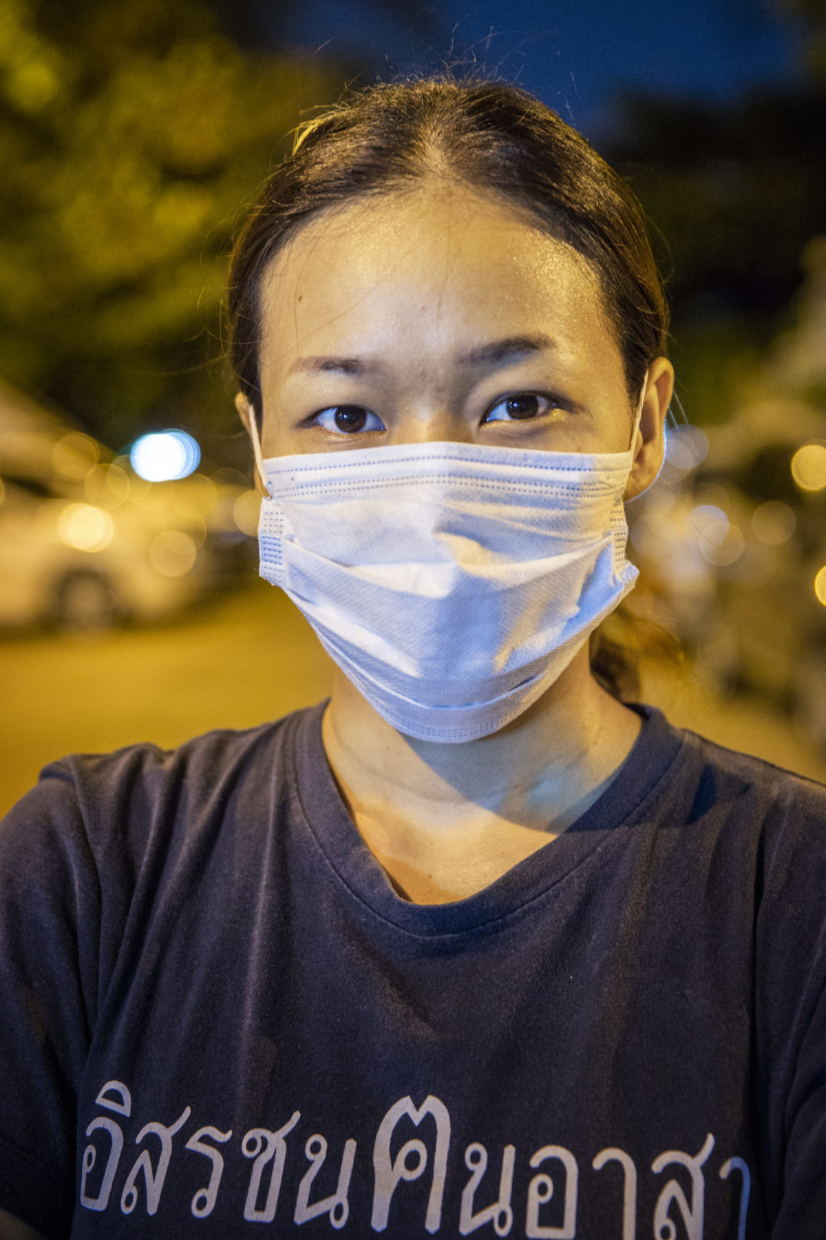 A masked person lit by streetlamps. 