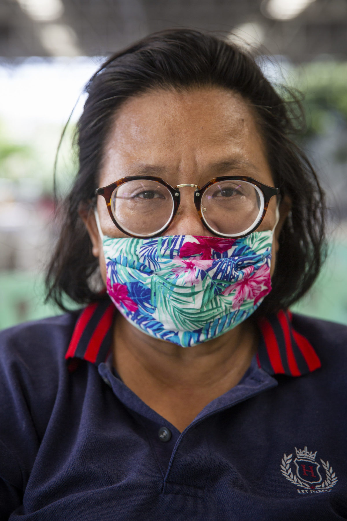 A person wearing a printed mask stands for their photo. 