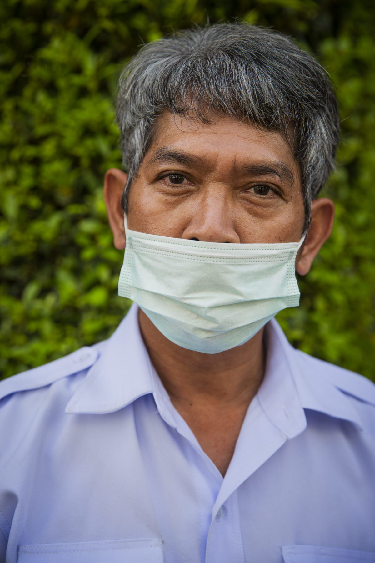 A person wearing a mask over their mouth sits for a photo. 