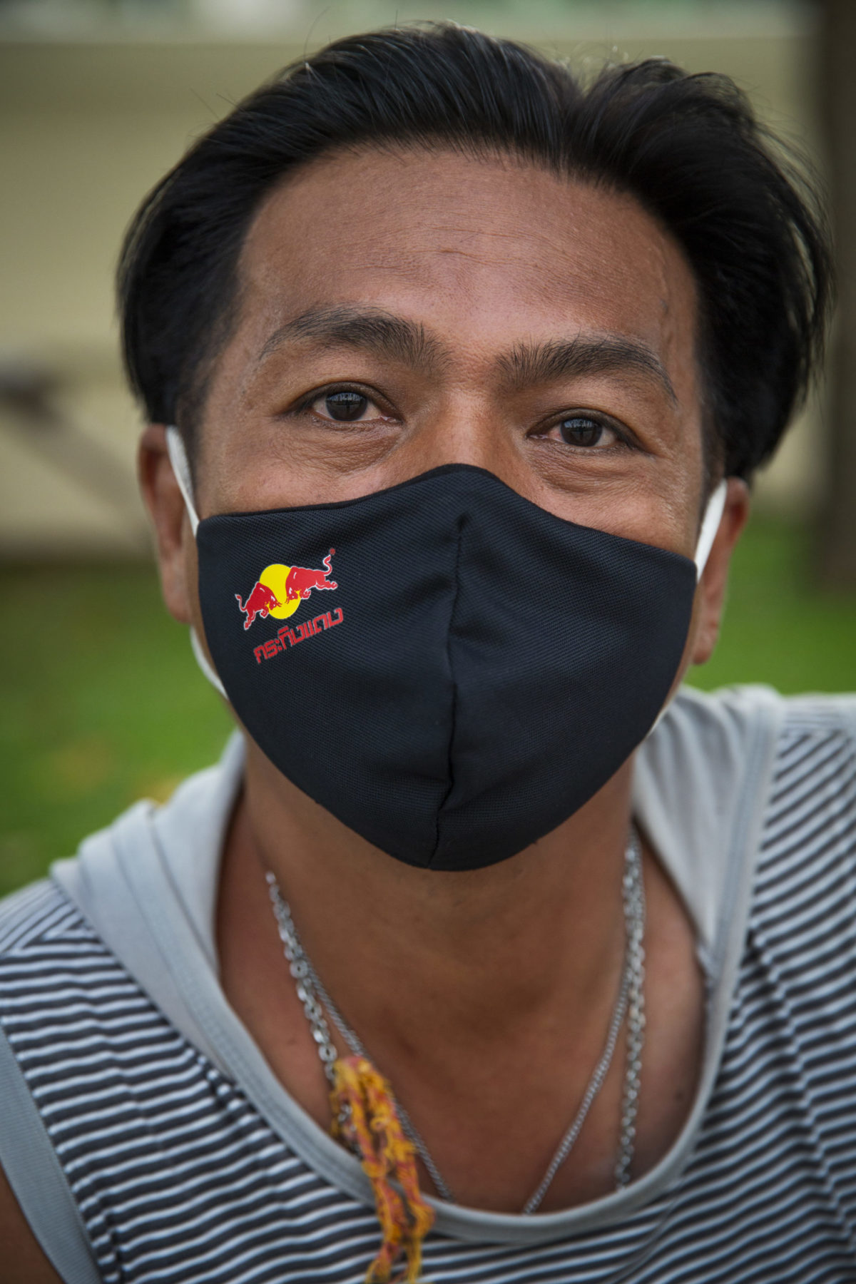 A person wearing a mask leans forward for their photo.