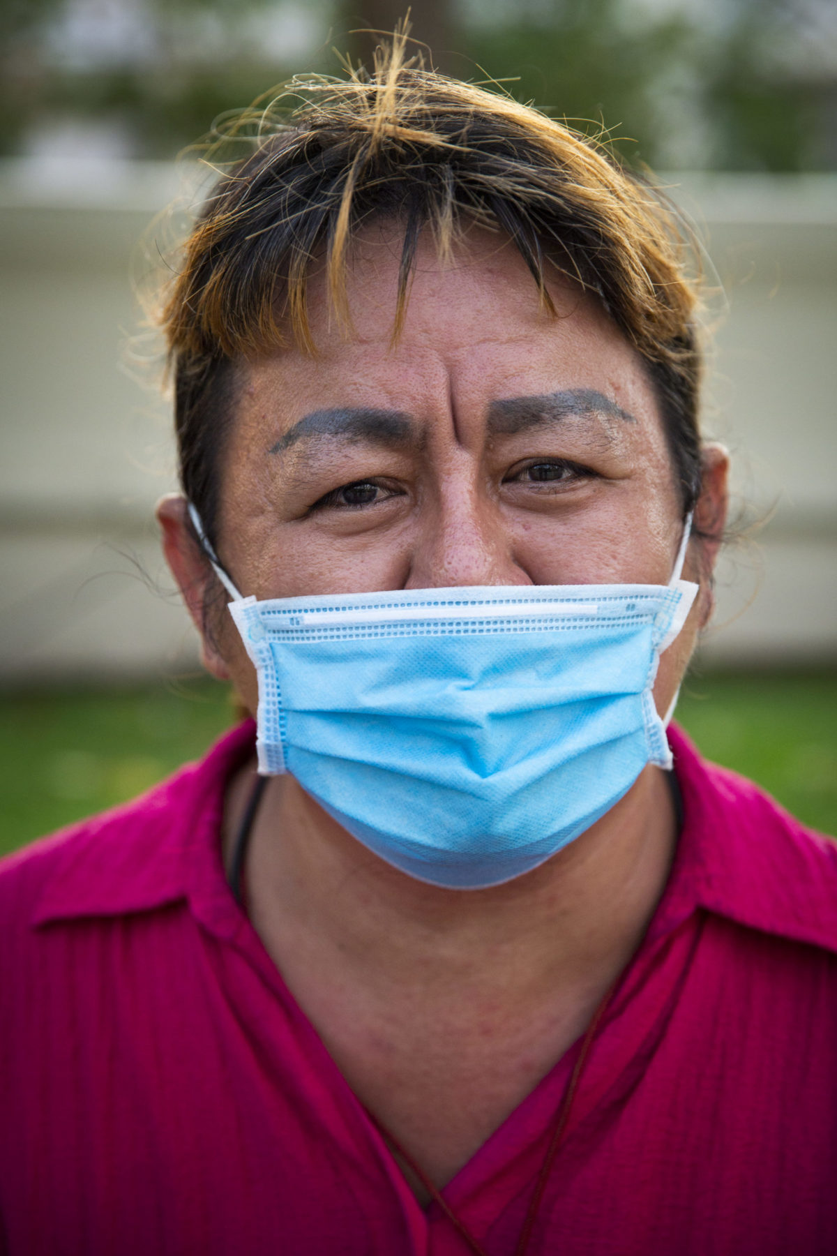 A person in a pink polo wears a mask. 