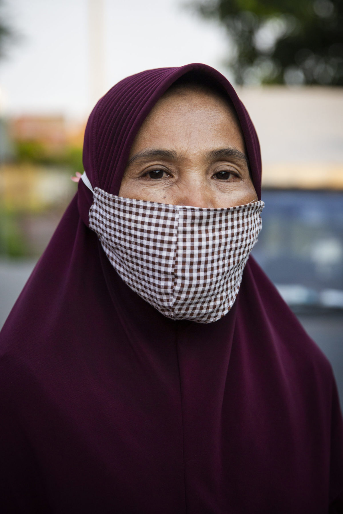 A person wearing a mask over their head covering. 