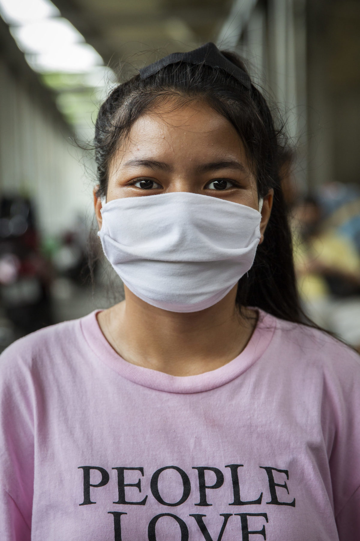 A person wears a pink shirt and white mask. 