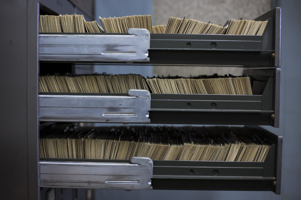 Three filing cabinet drawers are pulled out to reveal all of the cards filed inside. 
