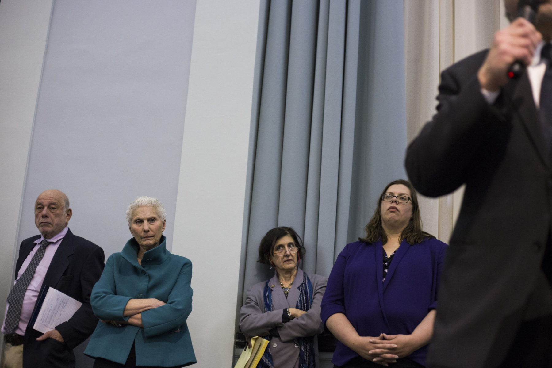 Group of people in suits leaning against wall