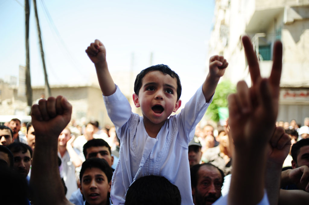 Child sitting on shoulders of person cheering