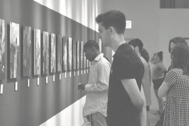 a black and white photograph of people viewing an art gallery