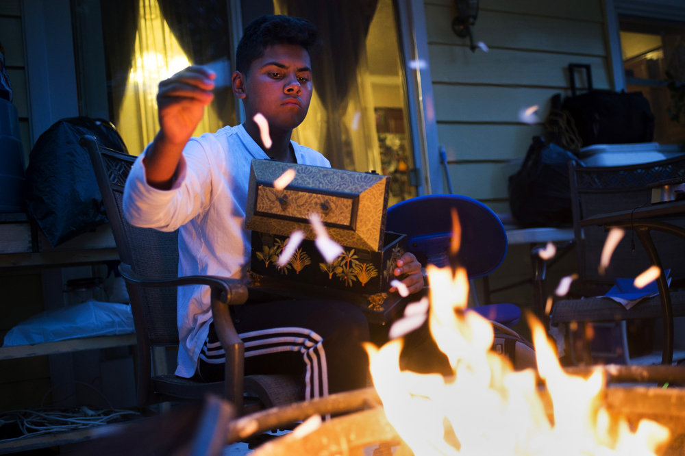 Bryan Quintana-Salazar, 13, throws torn-up paper from family documents into a fire on Friday, July 28, 2017 at his home in Ann Arbor, Michigan, USA. Anticipating his mother's deportation, the family burned important documents they no longer needed. Photo by Rachel Woolf.