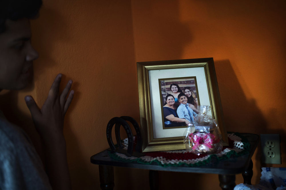 Bryan Quintana-Salazar, 13, looks at an old family photo on Friday, Oct. 20, 2017 at his father's old house in San Nicols, Mexico. Quintana-Salazar's mother suggested the family take the photo to send to her husband, after he was deported from the United States. This was the first time Quintana-Salazar had seen the photo displayed in his father's old house. Photo by Rachel Woolf.