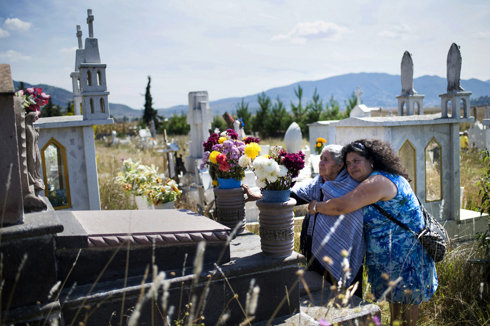 From left, Carlota Bertha Salazar puts her hand on her husband's grave as her daughter, Lourdes Salazar Bautista, hugs her on Sunday, Oct. 22, 2017 at the cemetery in San Nicols, Mexico. Bautista missed her father's funeral when she was living in the United States and could not come back to Mexico, until she was deported. Photo by Rachel Woolf.
