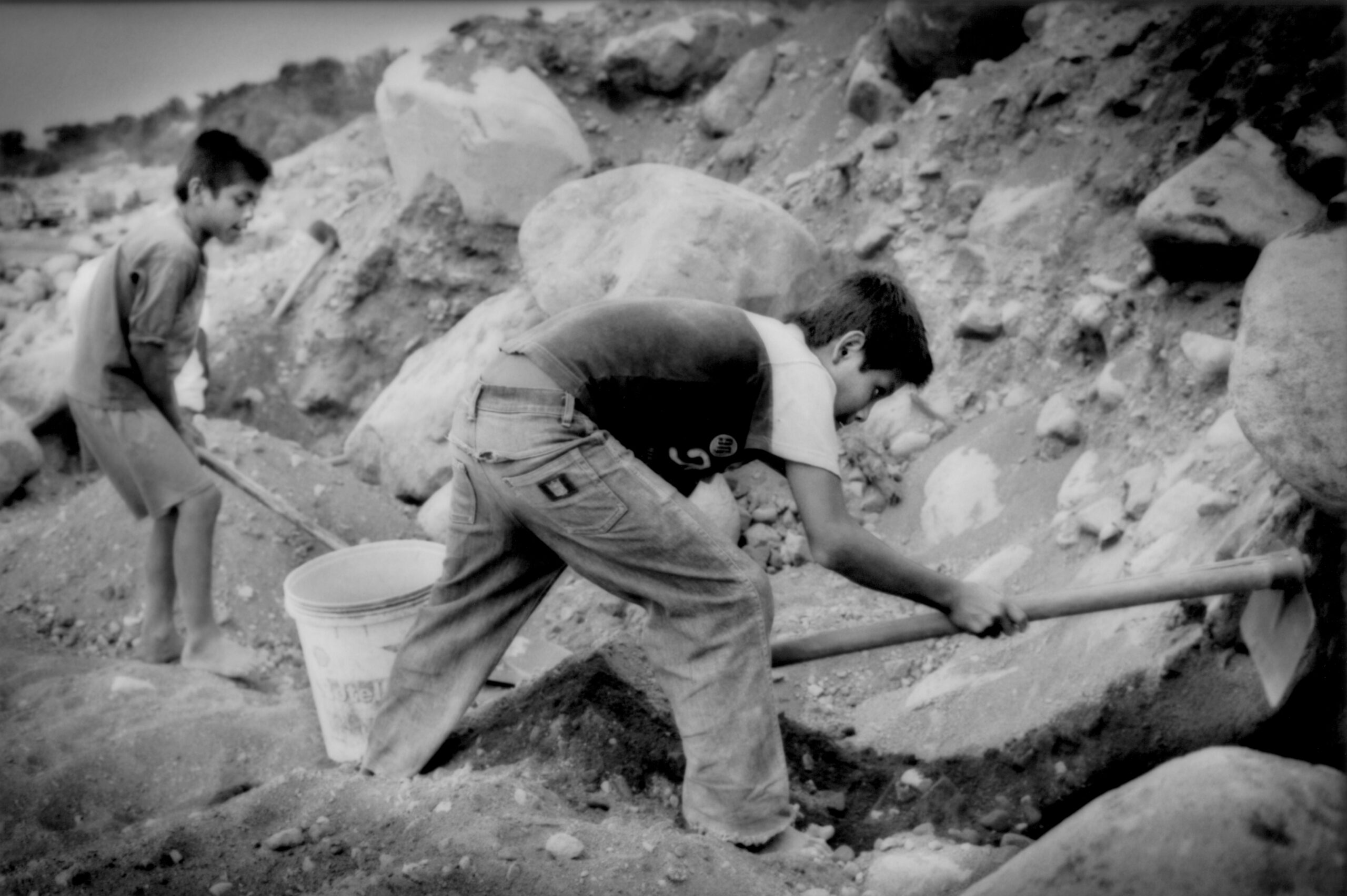 A young boy manually excavates a river bank for stones in Retalhuleu Province, Guatemala.